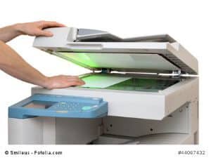 Kopiergerät im Einsatz: Hände legen ein Blatt Papier ins Gerät